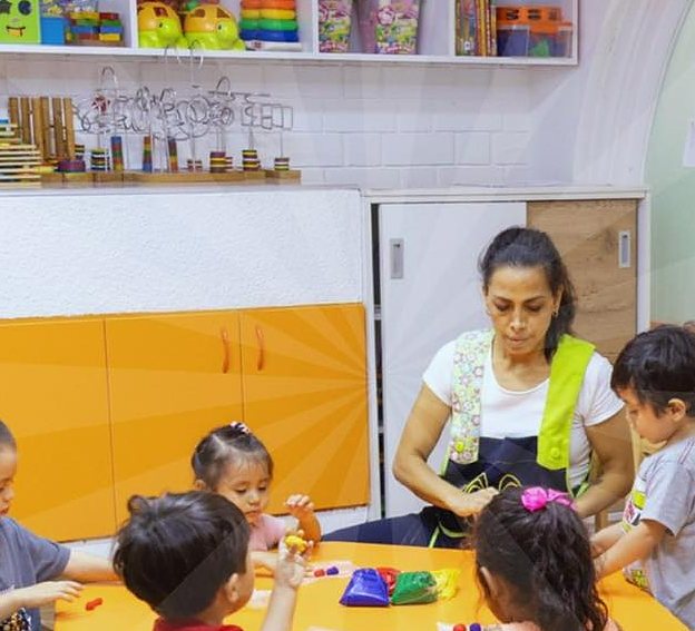 Una miss acompaña a un grupo de peques en una mesa de actividades del aula