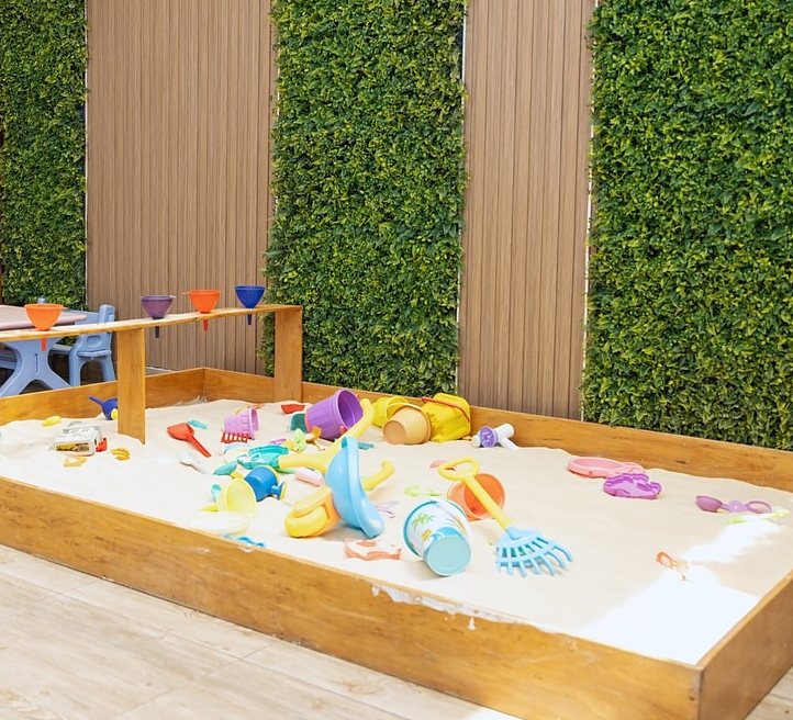 El arenero de Little Stars, con juguetes de arena, entre muros verdes