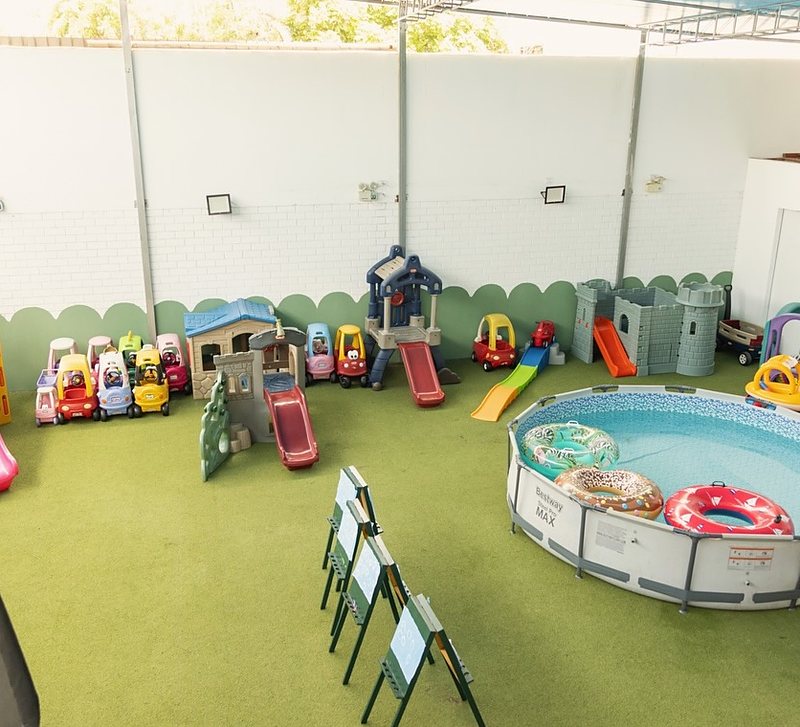 Jardín de juego con césped, carritos, casitas y piscina